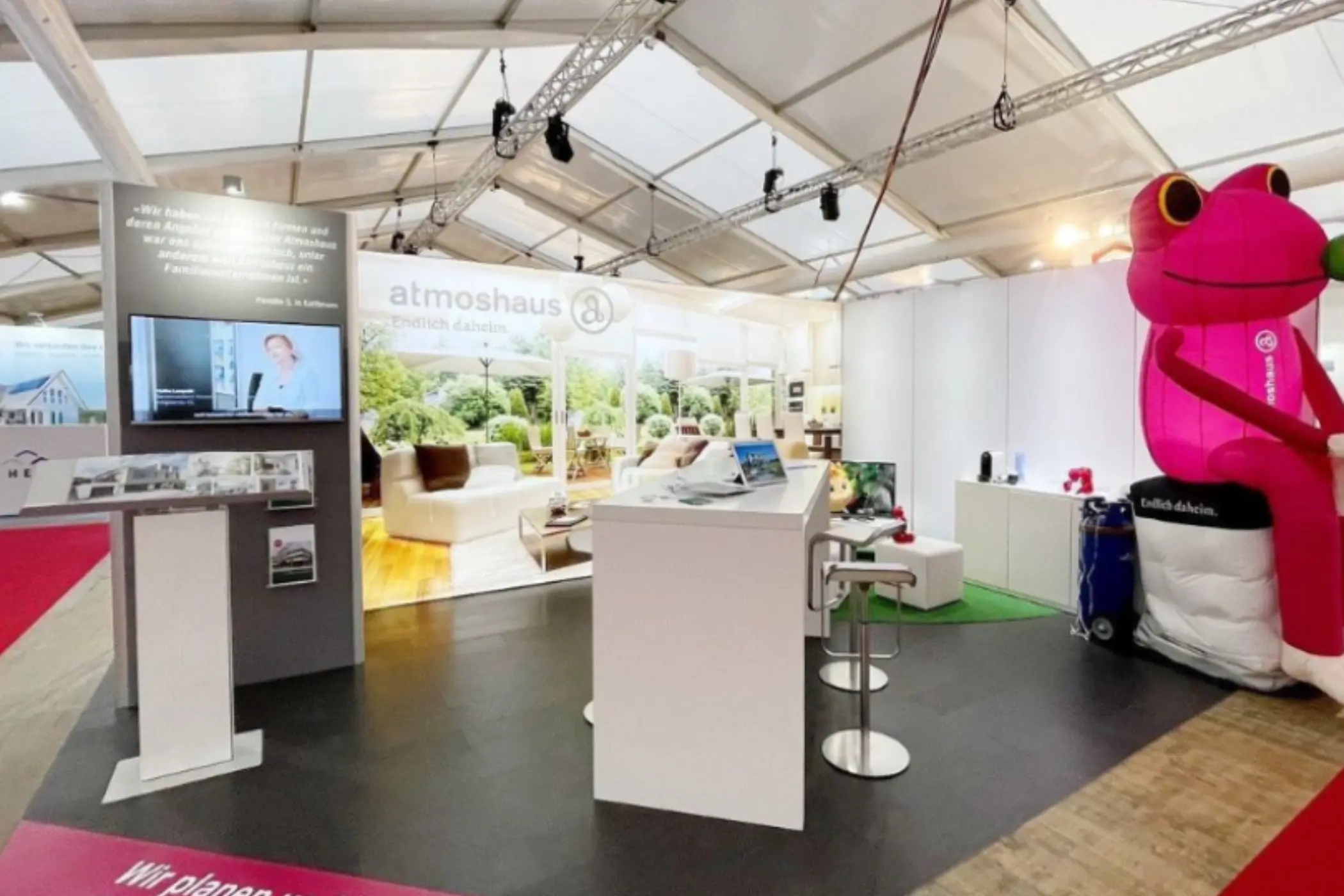 Moderner Messestand von atmoshaus mit Infotheke, Wohnraumvisualisierung und Beratungsbereich auf der Messe in Wettingen.