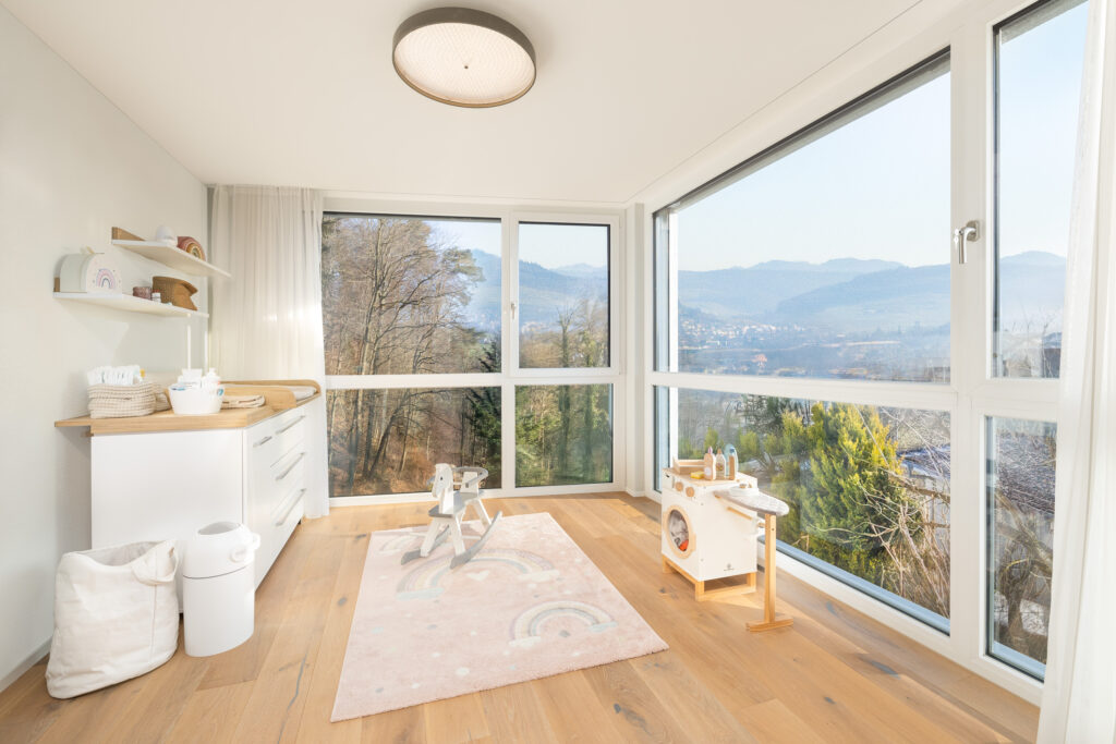 Ruhiges Babyzimmer mit viel Tageslicht und Blick ins Grüne.