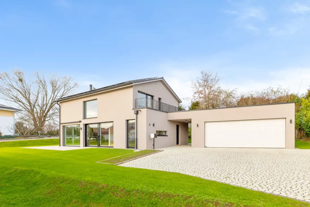 Modernes Neubauhaus mit klarer Architektur, weiten Fensterflächen, integrierter Garage und gepflegtem Garten in ruhiger Lage.
