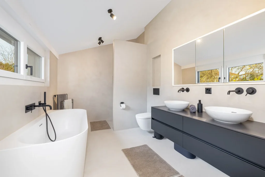 Modernes Badezimmer mit Badewanne, Doppelwaschbecken, WC und integrierter Beleuchtung.
