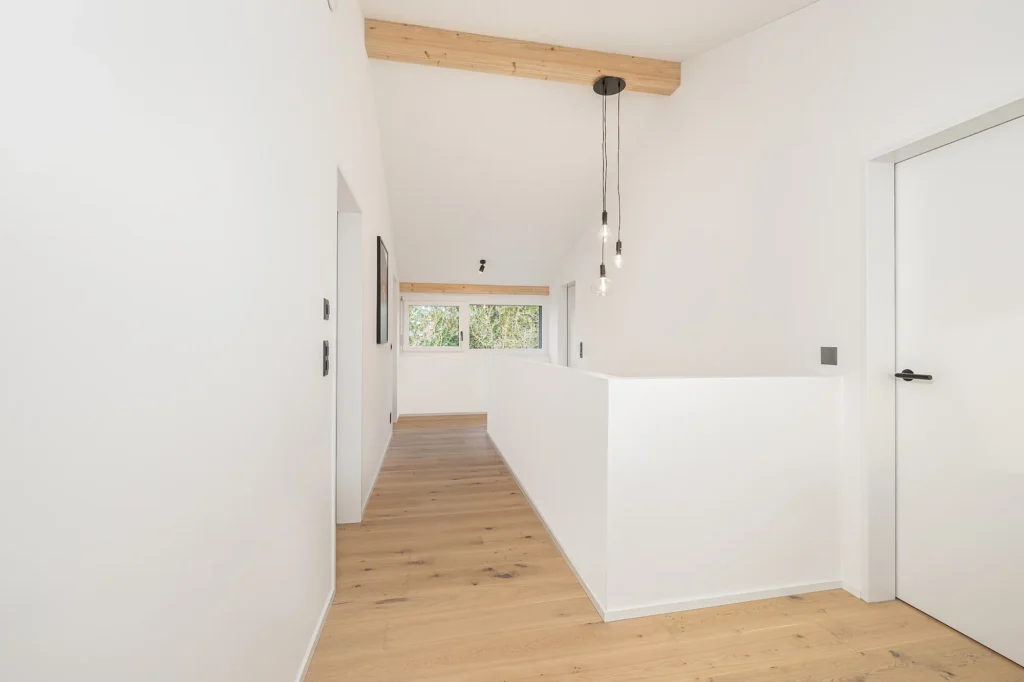 Heller Flur im Obergeschoss mit Holzdecke, Galeriebrüstung und natürlichem Lichteinfall.