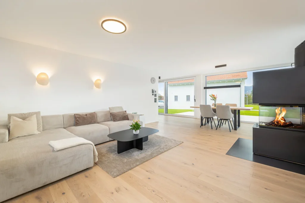 Wohnbereich mit Sofaecke, angrenzendem Essplatz und fliessendem Übergang zum Aussenraum.