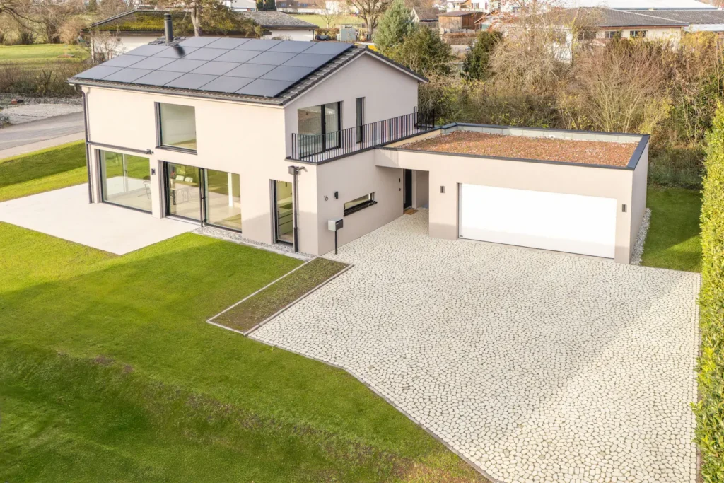 Architektenhaus Buch Vogelperspektive auf Grosszügiger, gepflästerter Vorplatz mit Zufahrt zur begrünten Garage,