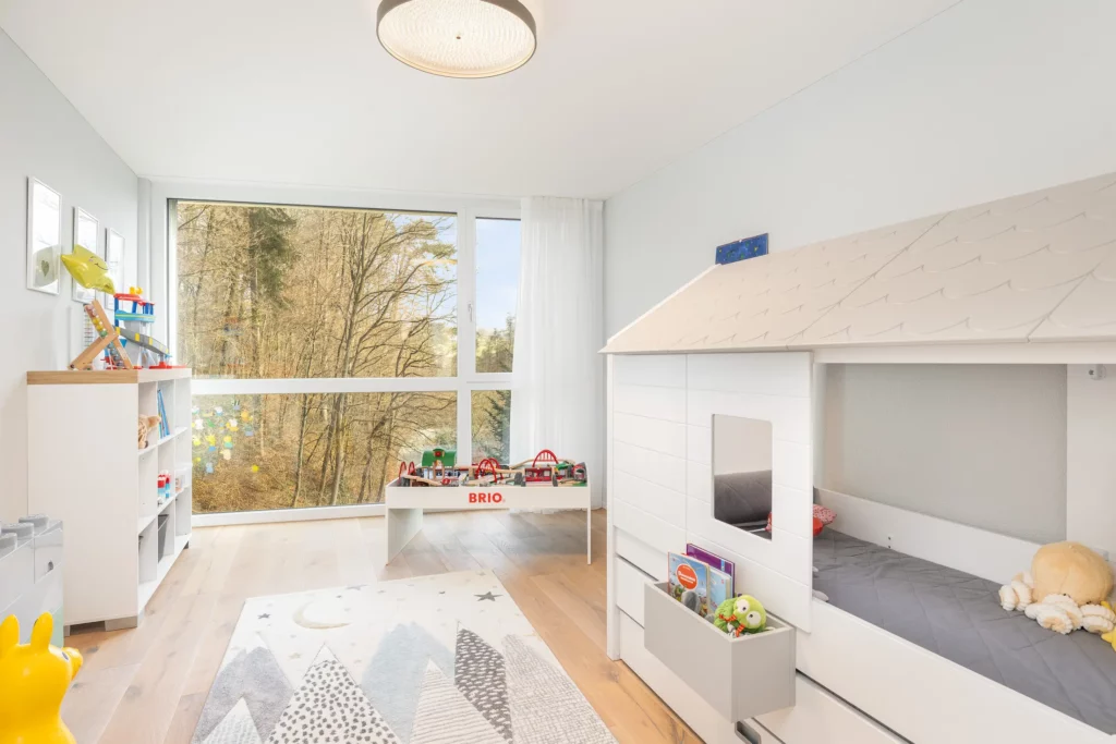 Freundliches Kinderzimmer mit Spielmöbeln und viel Tageslicht.
