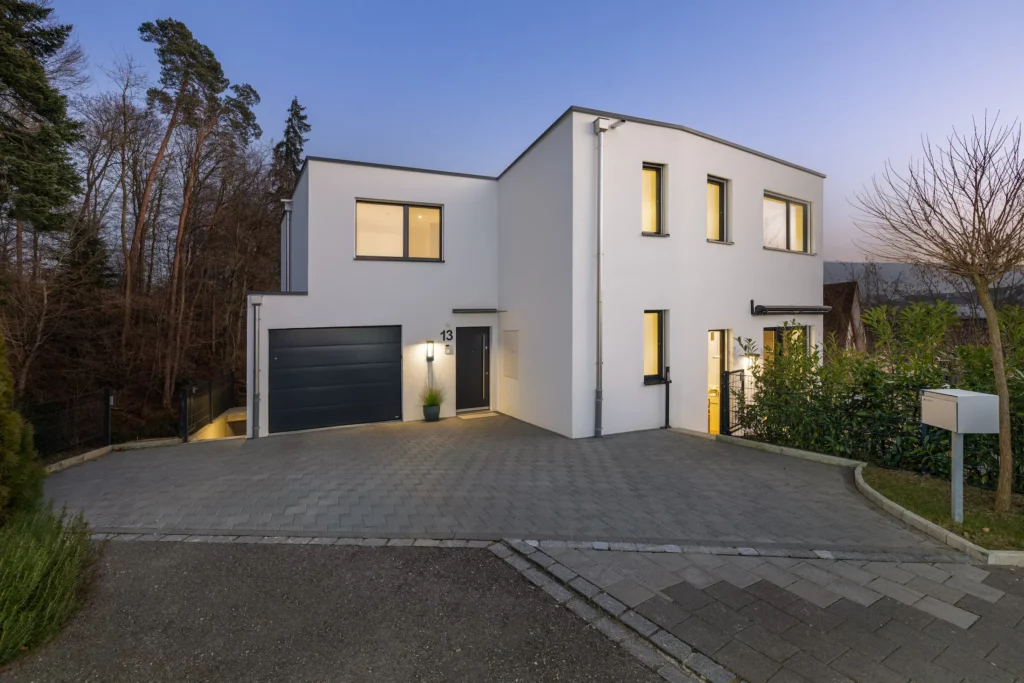 Einfamilienhaus mit Garage und Hauseingang bei Dämmerung.