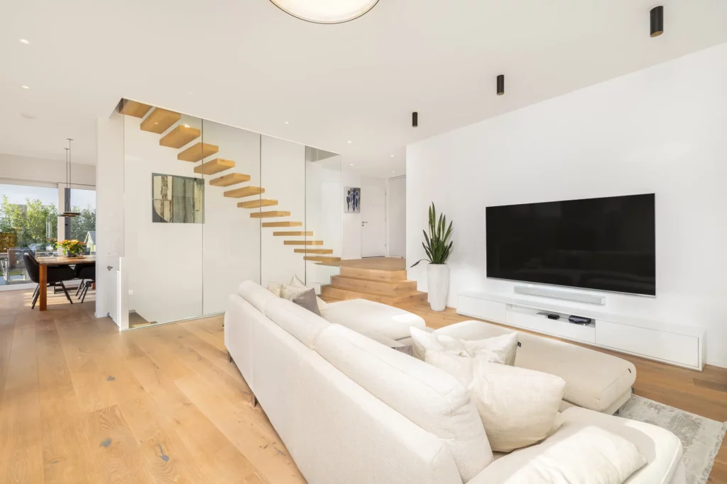 Offenes Wohnzimmer mit eleganter Treppe und viel Tageslicht.