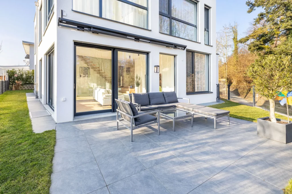 Terrasse mit Sitzmöbeln und direktem Zugang zum Wohnbereich eines Einfamilienhauses.