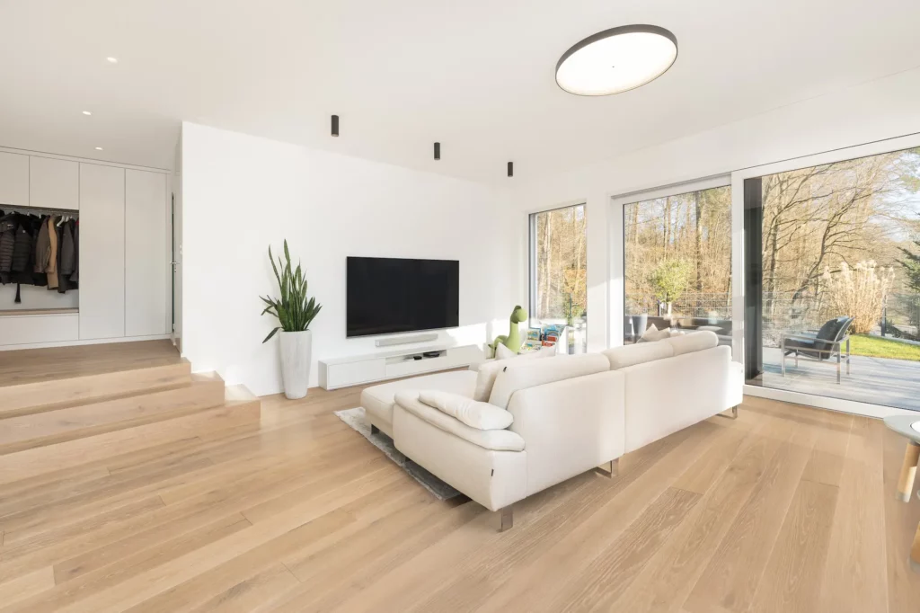 Heller Wohnbereich mit Sofa, Fernseher und Zugang zur Terrasse.