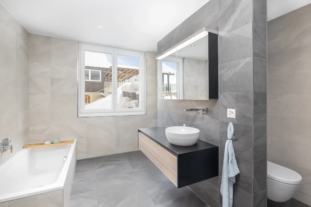 Badezimmer mit Badewanne, Waschtisch und Fenster.