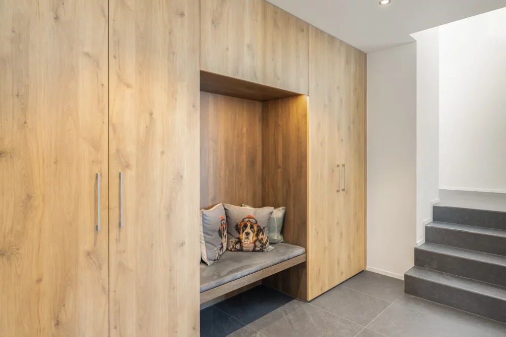 Offener Eingangsbereich mit maßgefertigter Garderobe aus Holz und integrierter Sitznische