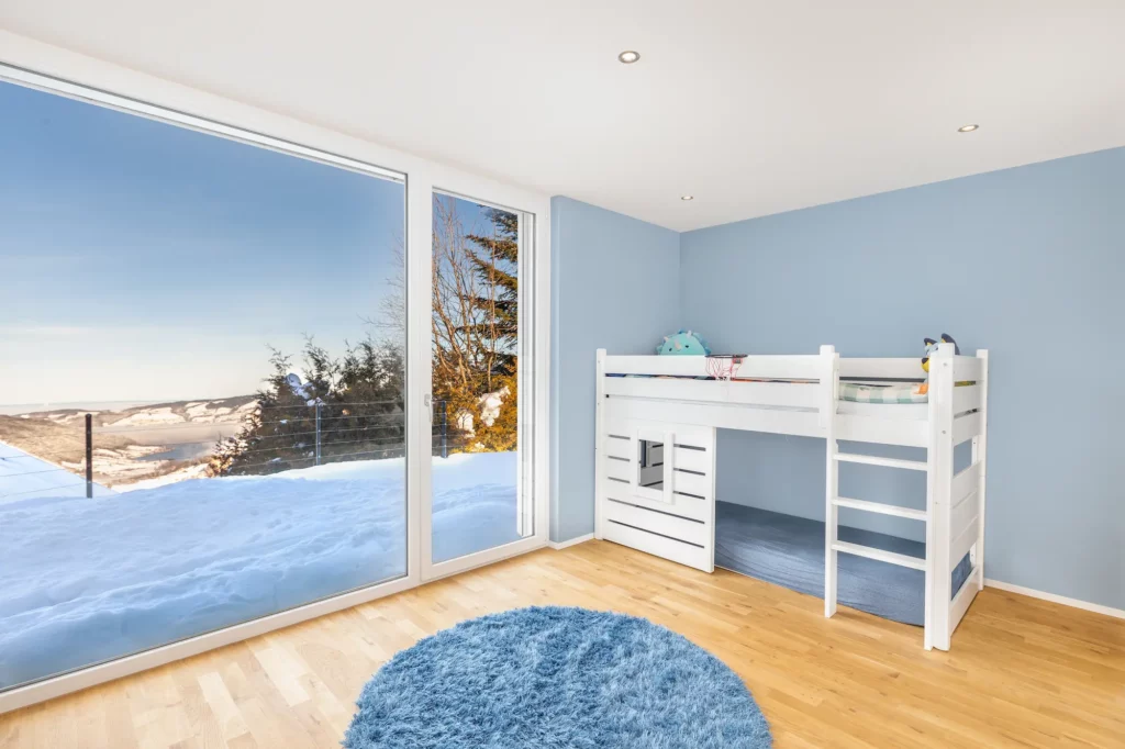 Helles Kinderzimmer mit Hochbett und bodentiefem Fenster.