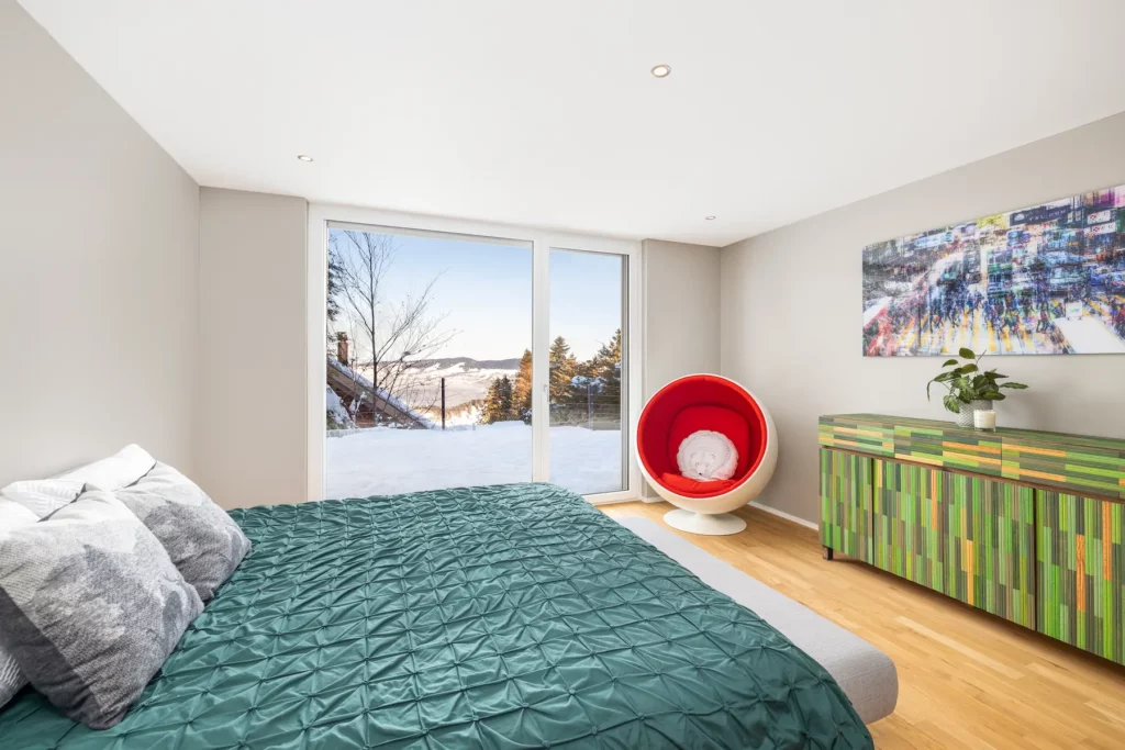 Schlafzimmer mit großem Fenster, Doppelbett und Blick ins Freie.