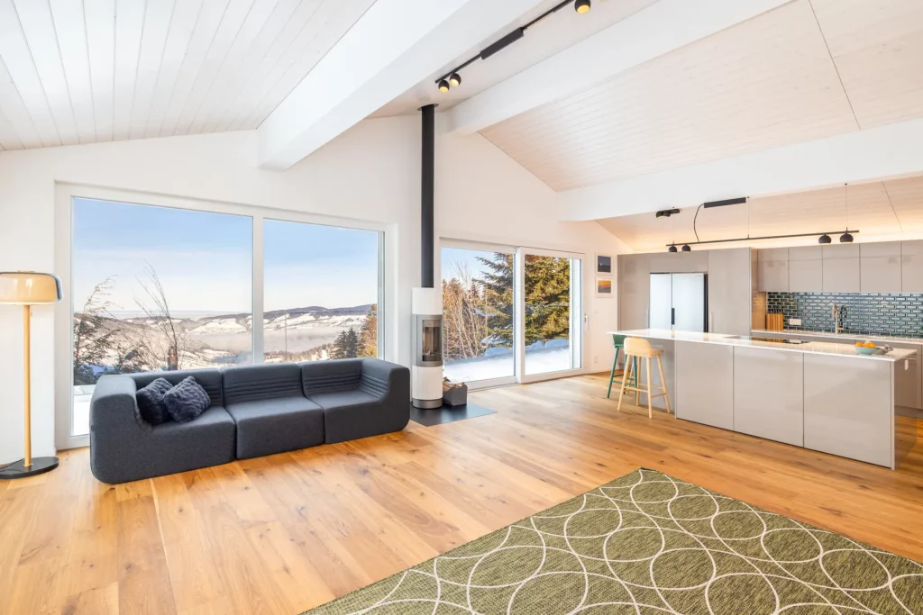 Großzügiger Wohnbereich mit Sofa, Kamin und bodentiefen Fenstern mit Panoramablick