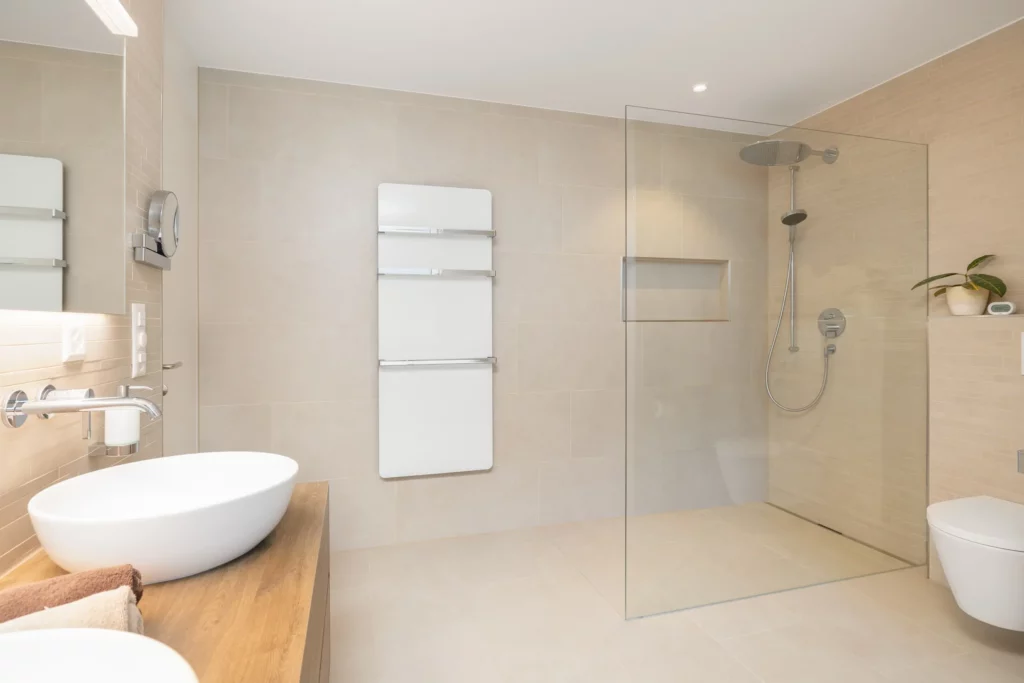 Badezimmer mit bodengleicher Dusche und Glasabtrennung.