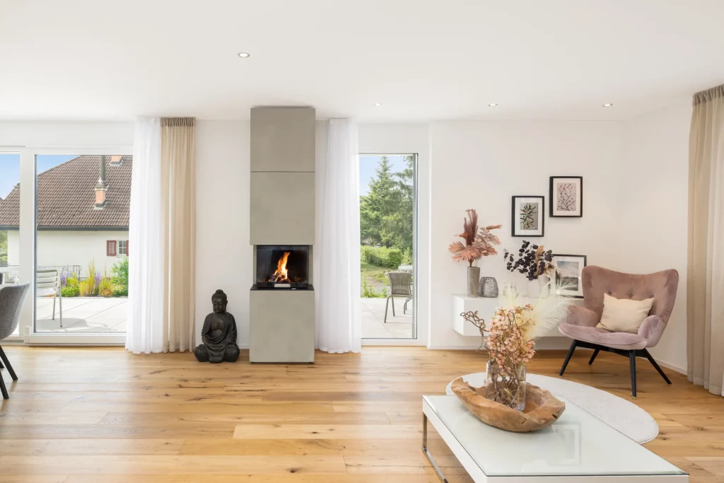 Wohnbereich mit Kamin, Holzboden und großen Fenstern mit Zugang zur Terrasse.